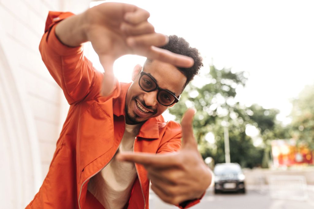 A young man shaping his fingers as if framing the camera.